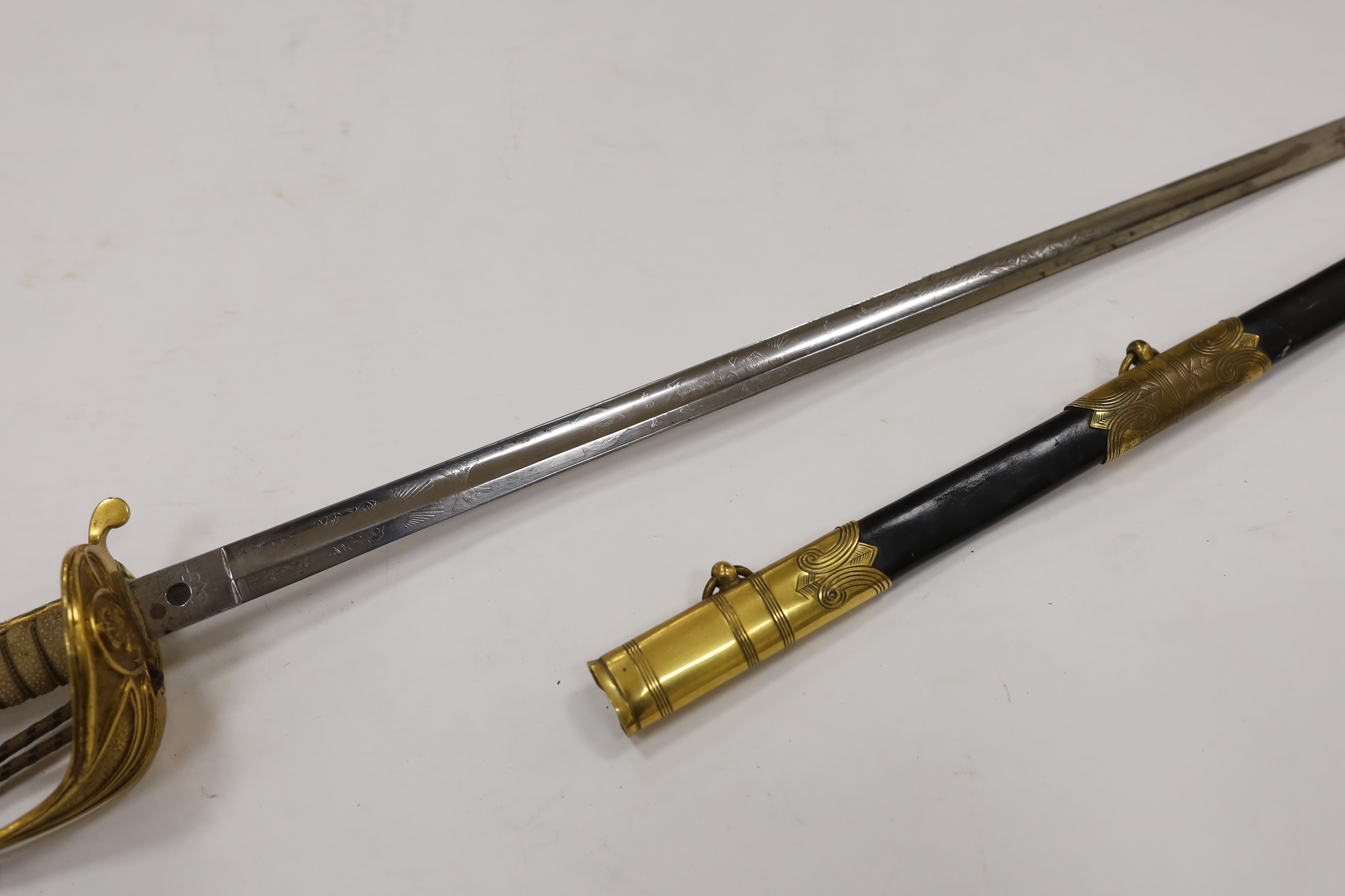 A World War I naval sword with folding guard engraved J.W. Collett R.N., regulation gilt hilt and scabbard mounts, the blade has been refinished and furniture regilded, with bullion dress knot, blade 78.5cm